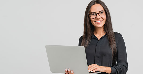 A young woman wearing glasses holding a laptop computer.