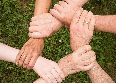 A closeup of six hands clasping wrists to form a circle.